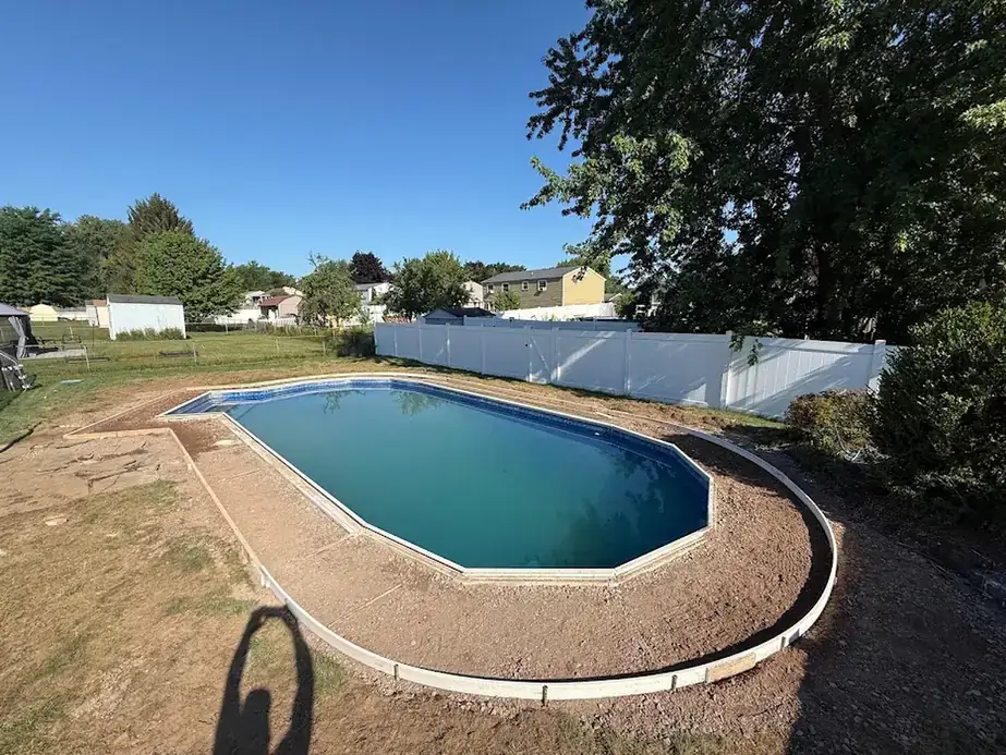 Wood forms staked around a pool on bare graded soil ahead of the deck pour