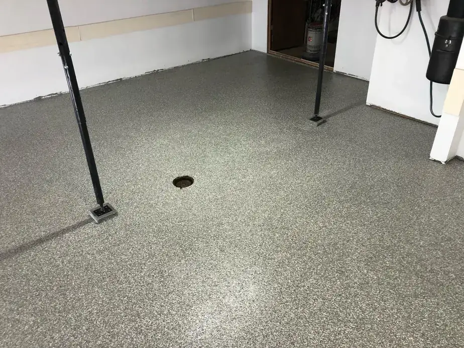 Speckled grey flake epoxy coating on a garage floor with a steel support post